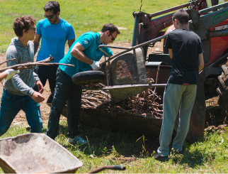 Teacher and students putting wood in tractor