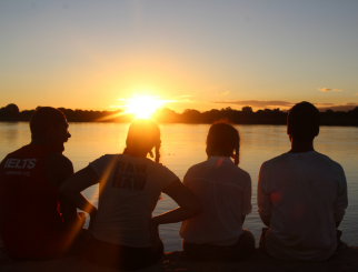 Young people sitting at a dock at sunset